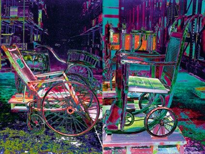 Two vintage wheelchairs raised on low plinths, photographed in the same electric solarized color, a cluttered interior behind them dissolving into the same palette.
