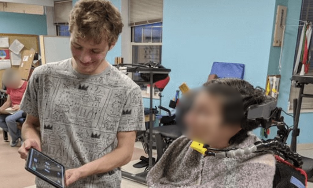 Student showing a tablet control interface to a powered wheelchair user during a co-design session.