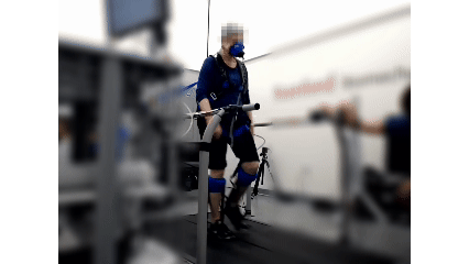 Older adult woman walking on a treadmill wearing ankle exoskeletons on both legs.
