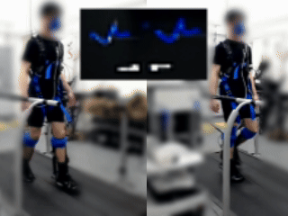 Young adult man walking on a treadmill with ankle exoskeletons on both legs while a screen shows real-time gait biofeedback.